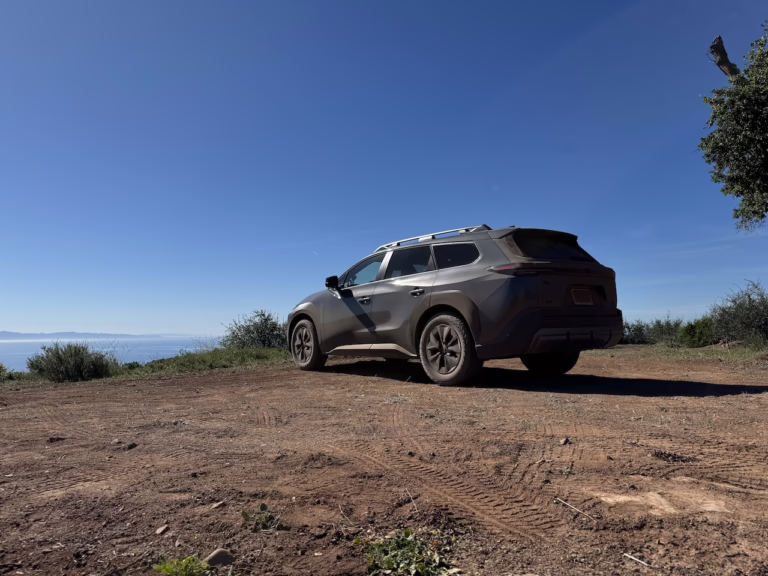2026 Toyota bZ Woodland rear 3/4, atop a vista, pointing toward the Pacific Ocean.